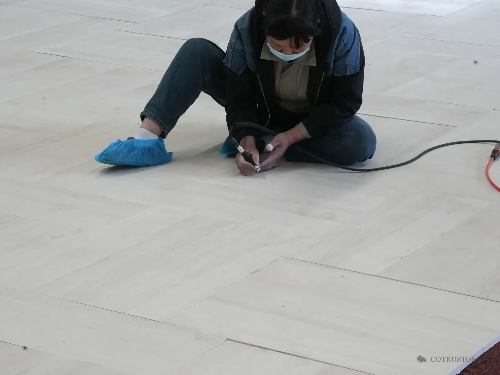 Worker using a small handheld tool on laid-out stone panels